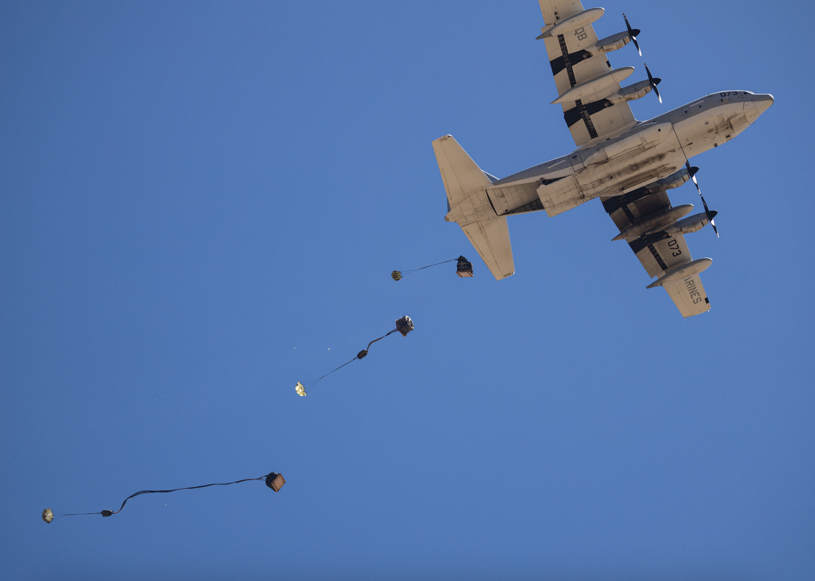 Marine Corps KC-130J Hercules transport aircraft flies overhead, releasing cargo for air delivery drop during Weapons and Tactics InstructorCourse 2-24 near Landing Zone Hatch, Yuma, Arizona, April 2, 2024 (U.S. Marine Corps/Hannah Hollerud)
